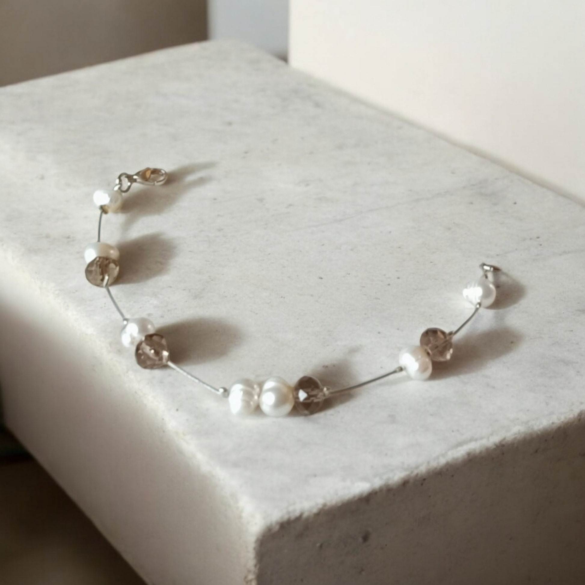 Bracelet perles de culture baroques blanches et perles en cristal facetté gris taupe, montées sur fil gainé argenté.
