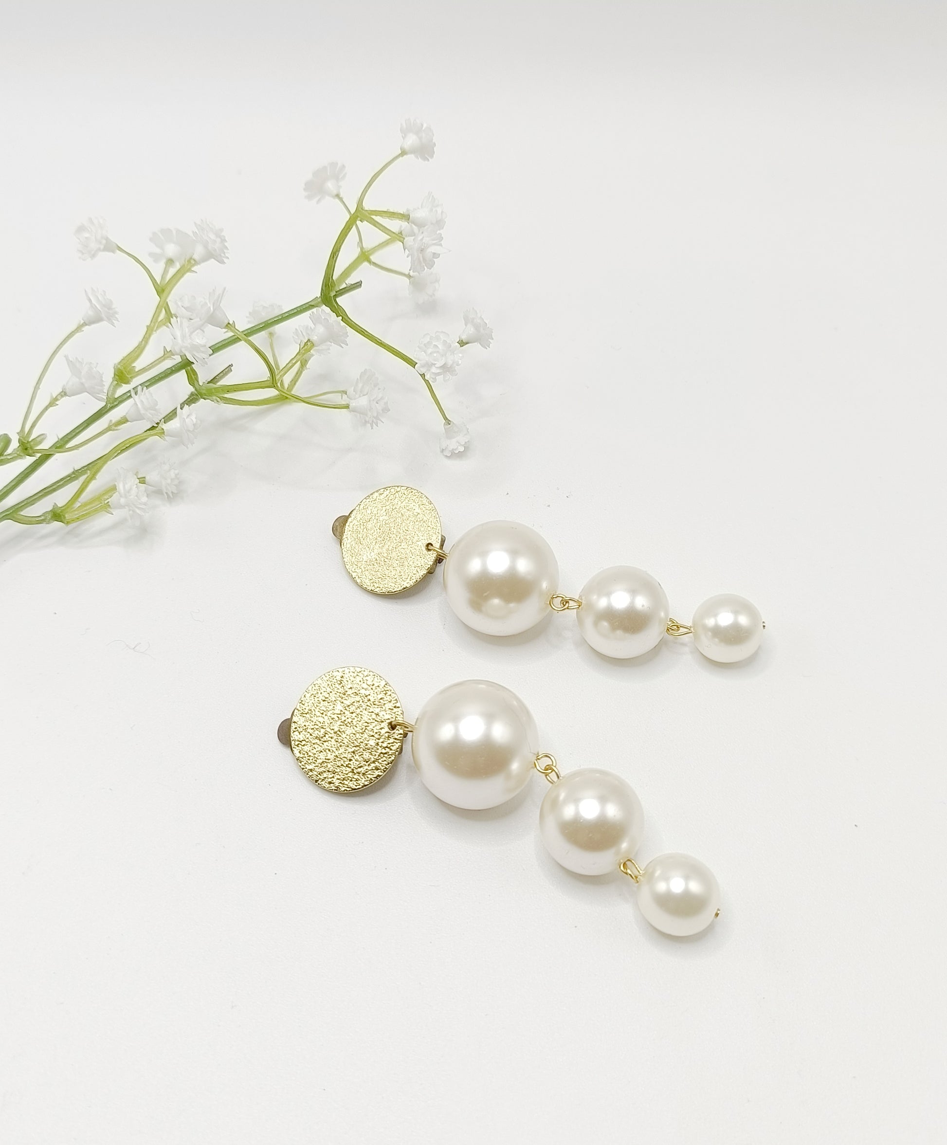 Les Cascades, grandes boucles d'oreilles clips dorés et trois perles blanches de taille différente en chute, très légères