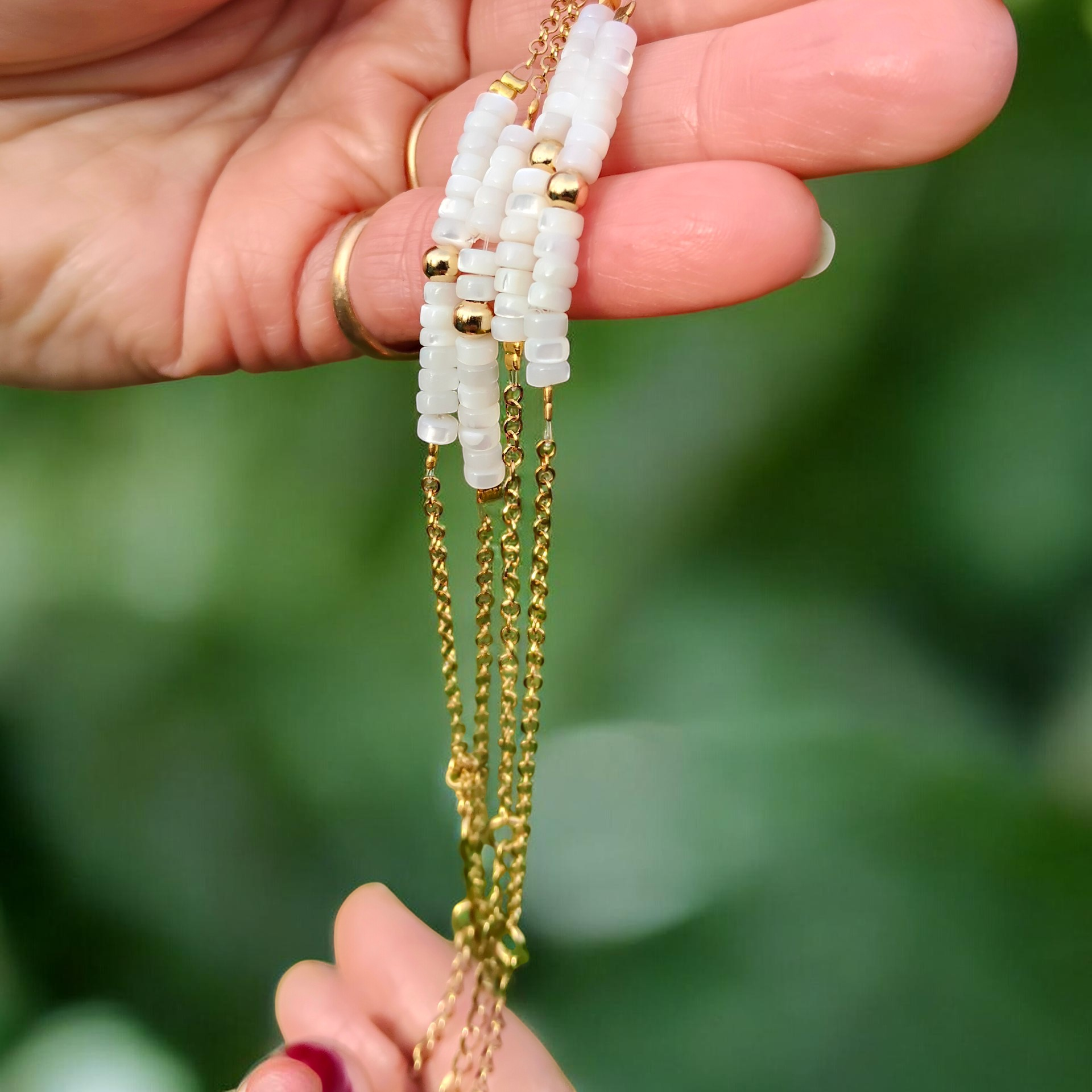 Lucien, le bracelet doré fin en acier inoxydable et ses petites rondelles en nacre blanche et perle dorée en acier inoxydable