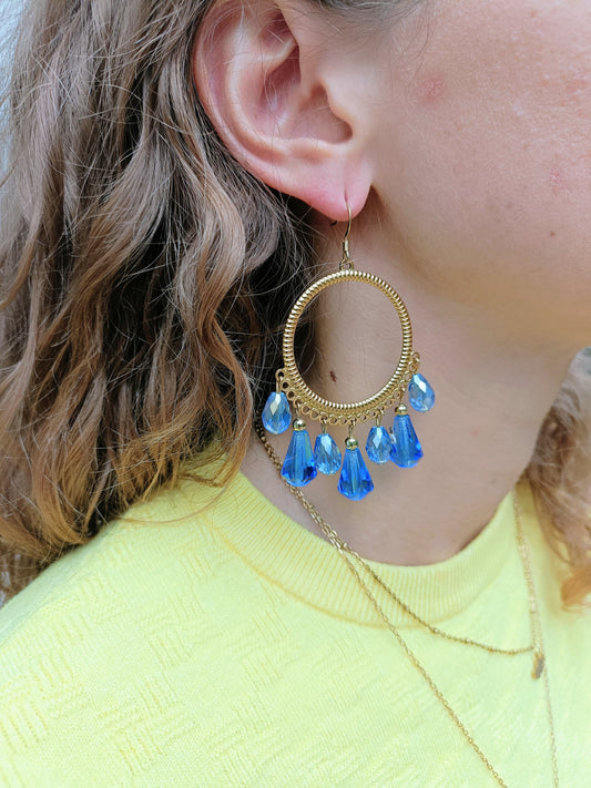 Ysambre, les grandes boucles d'oreilles rondes dorées or fin et perles gouttes bleues en cristal et verre facetté, disponibles en percées ou clips