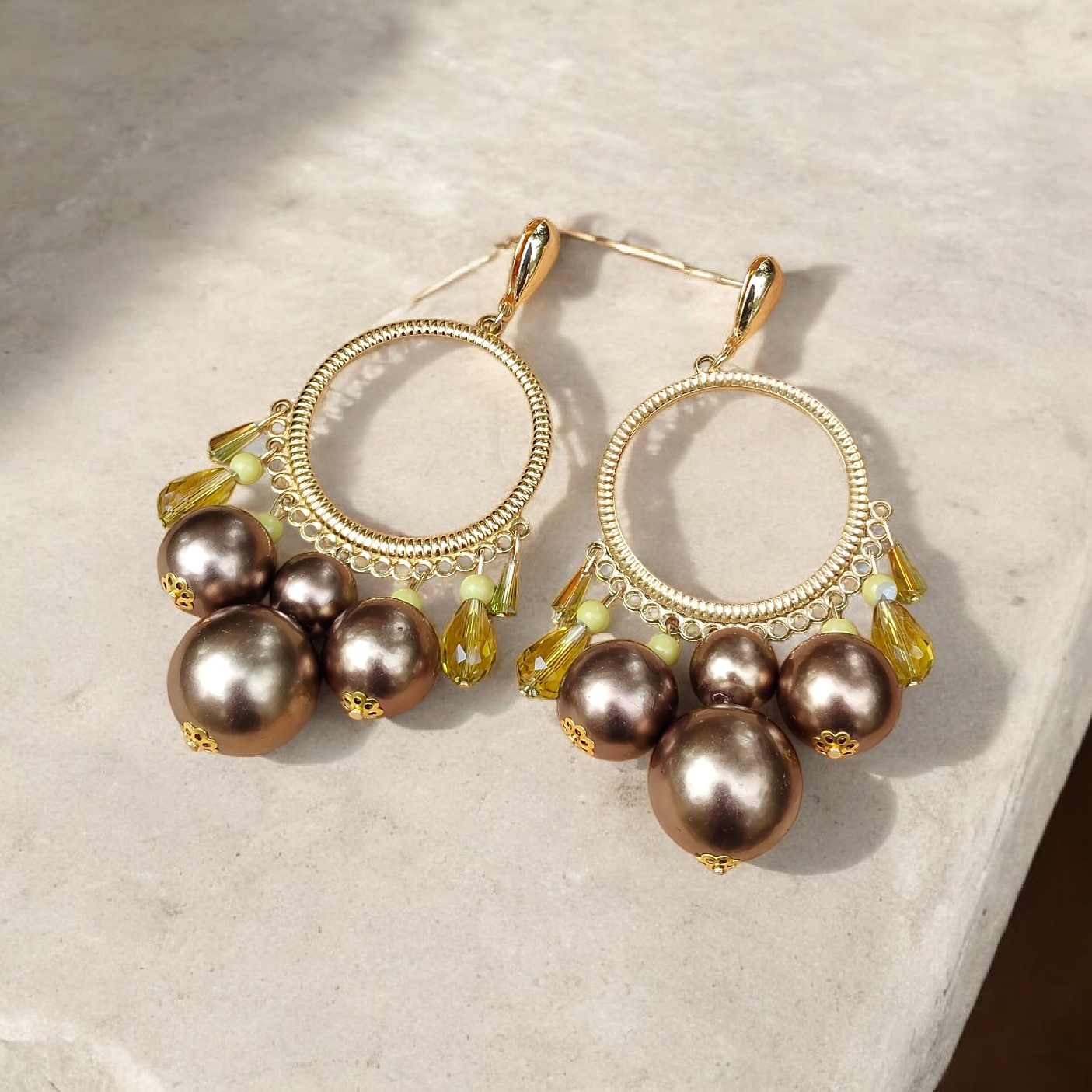 Les grandes boucles d'oreilles rondes  dorées or fin Ysambre mesurent 8 cm et sont composées de gouttes larmes dorées or fin et de perles bronze en acrylique, petites perles jaunes en verre et gouttes jaunes en verre facetté